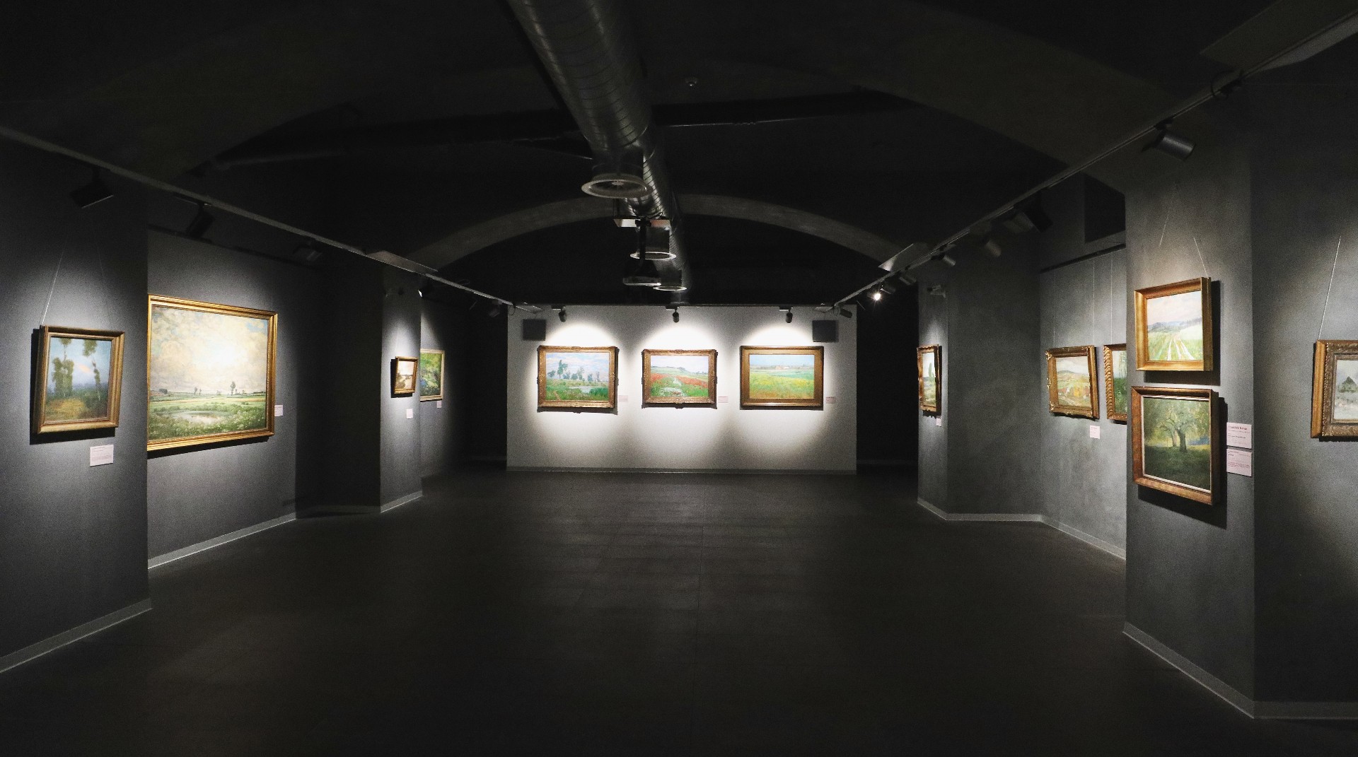 Pohled do expozice v Galerii ČS s trojicí Kavánových obrazů v čele sálu